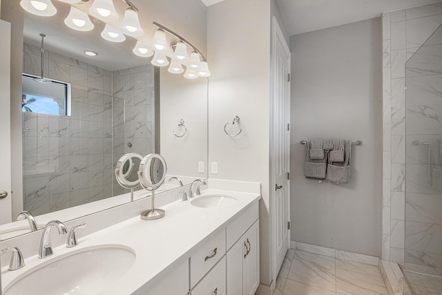 bathroom featuring double vanity, marble finish floor, tiled shower, and a sink