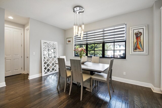 dining area featuring dark wood-style floors, a chandelier, and baseboards