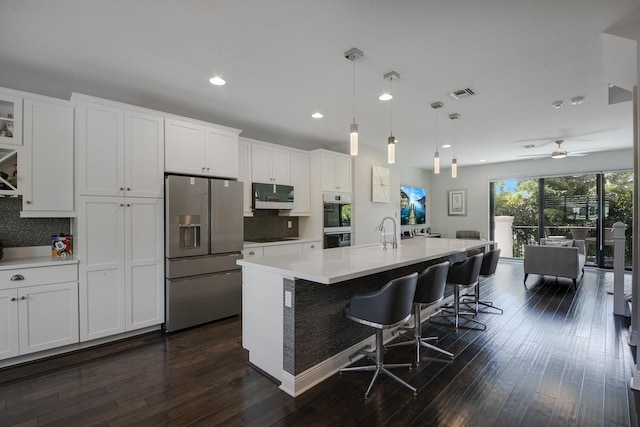 kitchen featuring stainless steel appliances, visible vents, white cabinets, light countertops, and dark wood-style floors