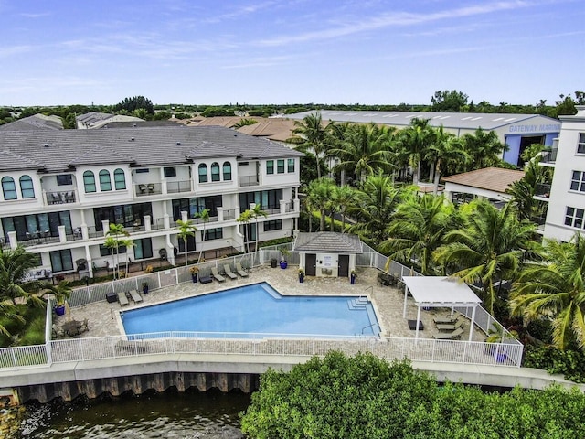 pool with a patio area, a water view, fence, and an outdoor structure