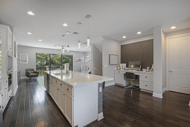 kitchen featuring open floor plan, light countertops, a sink, and white cabinets