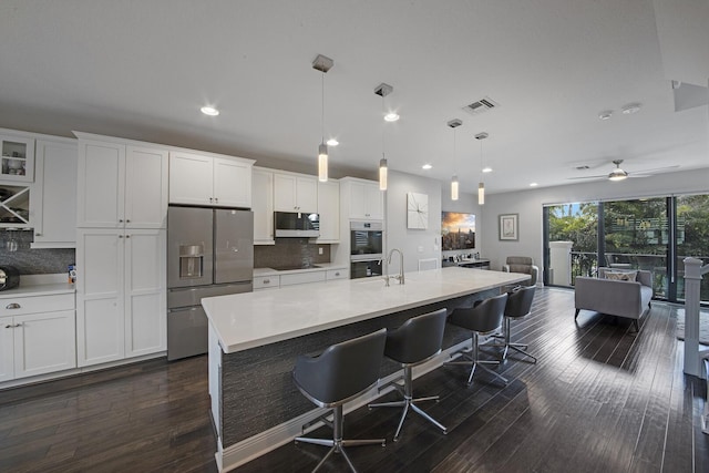 kitchen featuring visible vents, stainless steel appliances, a breakfast bar area, and light countertops