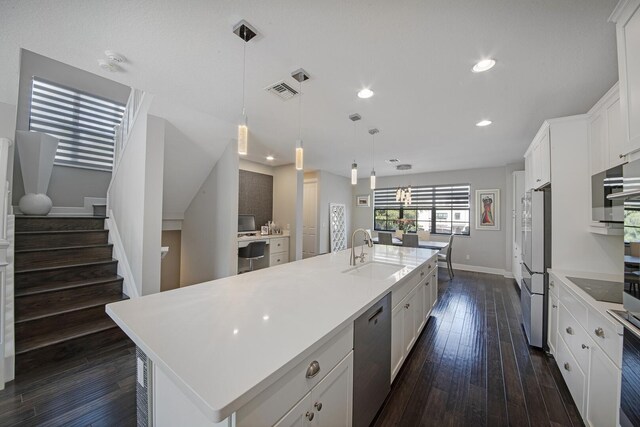 kitchen featuring visible vents, white cabinets, built in study area, open floor plan, and a sink