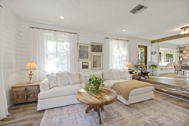 living room with hardwood / wood-style flooring, a textured ceiling, and wood walls