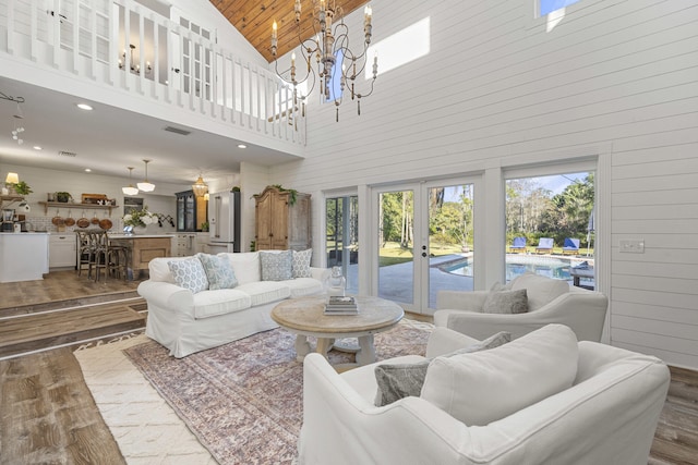 living room with hardwood / wood-style flooring, wooden walls, french doors, and a chandelier