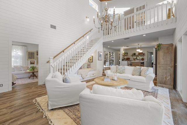 living room with wood-type flooring, a towering ceiling, and a notable chandelier