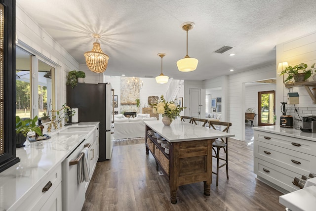 kitchen with pendant lighting, a fireplace, dishwasher, a breakfast bar area, and white cabinets