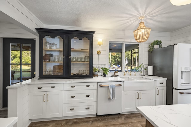 bar with dark wood-type flooring, fridge with ice dispenser, sink, hanging light fixtures, and dishwasher