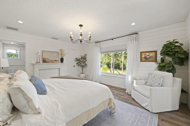 bedroom with multiple windows, hardwood / wood-style floors, and a textured ceiling