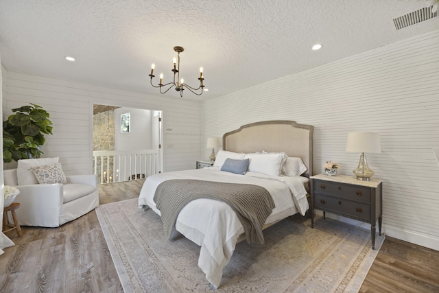 bedroom featuring hardwood / wood-style floors, a notable chandelier, and a textured ceiling