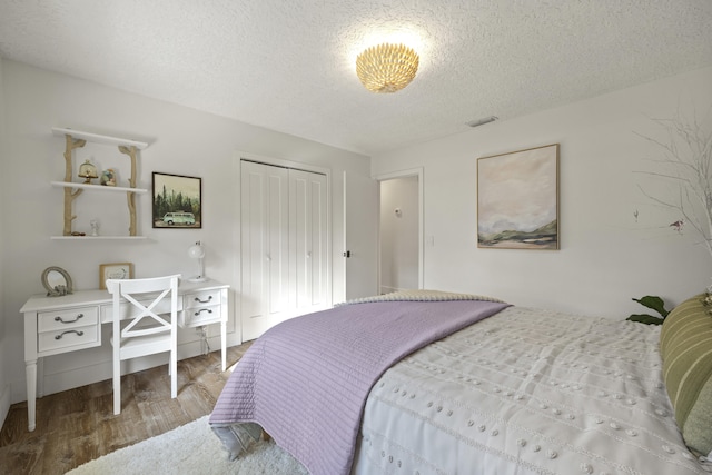 bedroom with a closet, hardwood / wood-style floors, and a textured ceiling