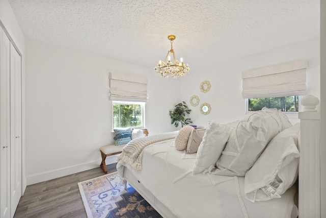 bedroom with an inviting chandelier, a closet, dark hardwood / wood-style floors, and a textured ceiling