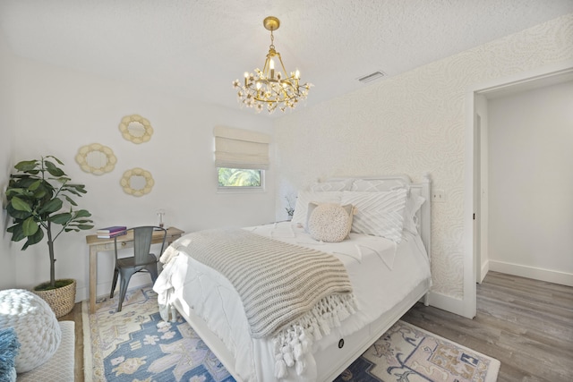 bedroom featuring hardwood / wood-style flooring, an inviting chandelier, and a textured ceiling