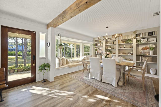 dining space featuring beam ceiling, hardwood / wood-style floors, a textured ceiling, and a chandelier