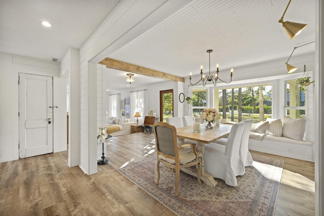 dining space with a notable chandelier, light hardwood / wood-style floors, and beamed ceiling