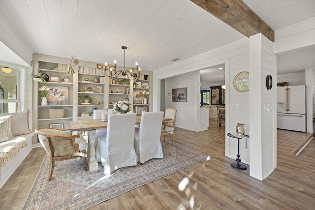 dining space featuring hardwood / wood-style flooring, wood ceiling, an inviting chandelier, and wood walls