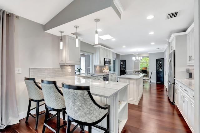 kitchen with hanging light fixtures, kitchen peninsula, white cabinets, and a kitchen island