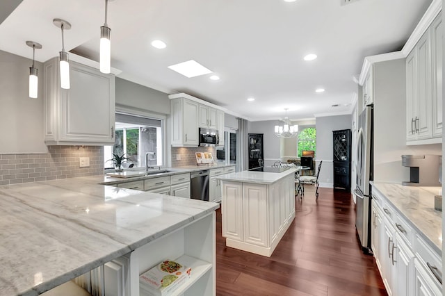 kitchen with pendant lighting, appliances with stainless steel finishes, kitchen peninsula, and white cabinets