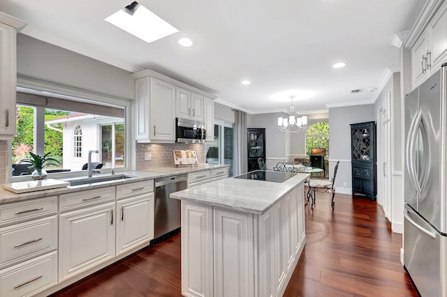 kitchen featuring sink, white cabinetry, crown molding, appliances with stainless steel finishes, and a kitchen island