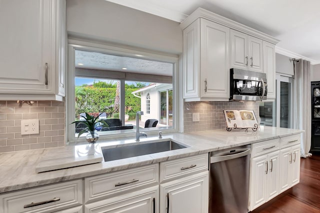 kitchen with stainless steel appliances, ornamental molding, white cabinets, and light stone counters