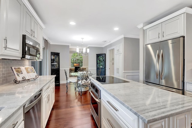 kitchen featuring a kitchen island, appliances with stainless steel finishes, white cabinets, light stone counters, and crown molding