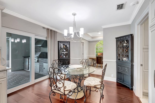 dining area featuring crown molding, a tray ceiling, dark hardwood / wood-style flooring, and a chandelier