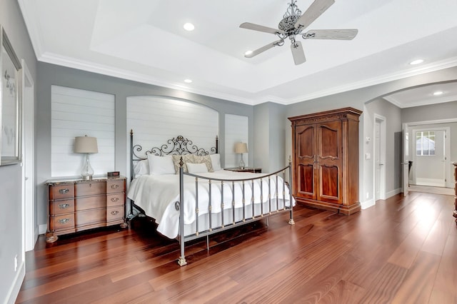 bedroom with dark hardwood / wood-style flooring, a tray ceiling, and ornamental molding