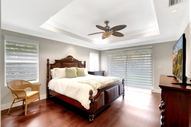 bedroom with crown molding, dark wood-type flooring, and a raised ceiling