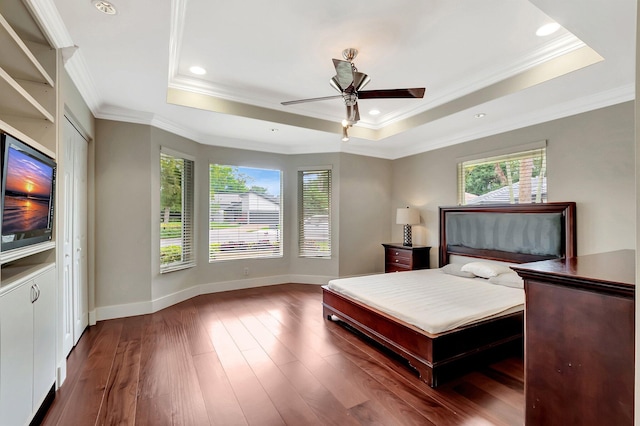 bedroom with crown molding, dark hardwood / wood-style floors, and a tray ceiling