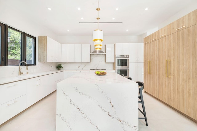 kitchen with a breakfast bar area, double oven, hanging light fixtures, a center island, and white cabinets