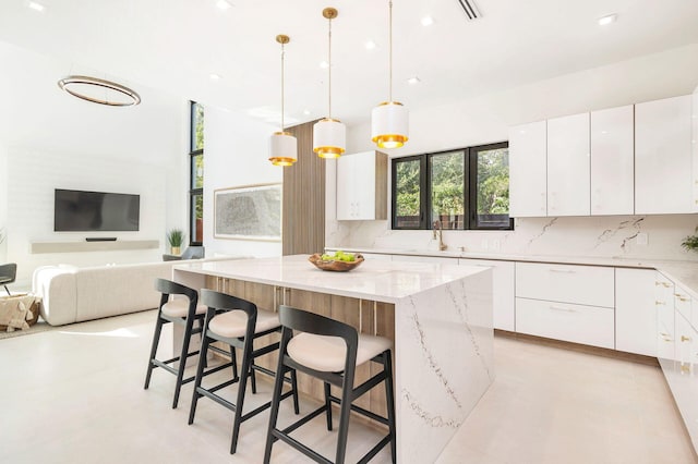 kitchen with hanging light fixtures, white cabinetry, a kitchen island, and light stone countertops