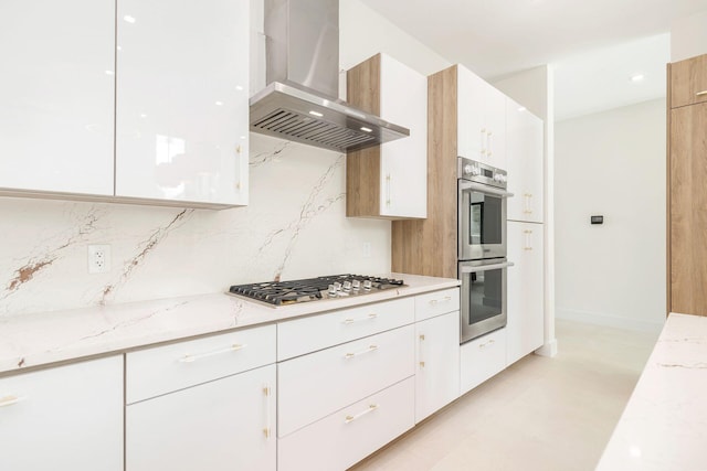 kitchen with light stone countertops, appliances with stainless steel finishes, white cabinets, and island exhaust hood