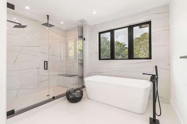 bathroom featuring plus walk in shower and tile walls