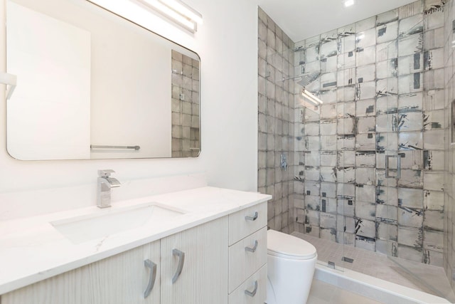 bathroom featuring vanity, toilet, and tiled shower