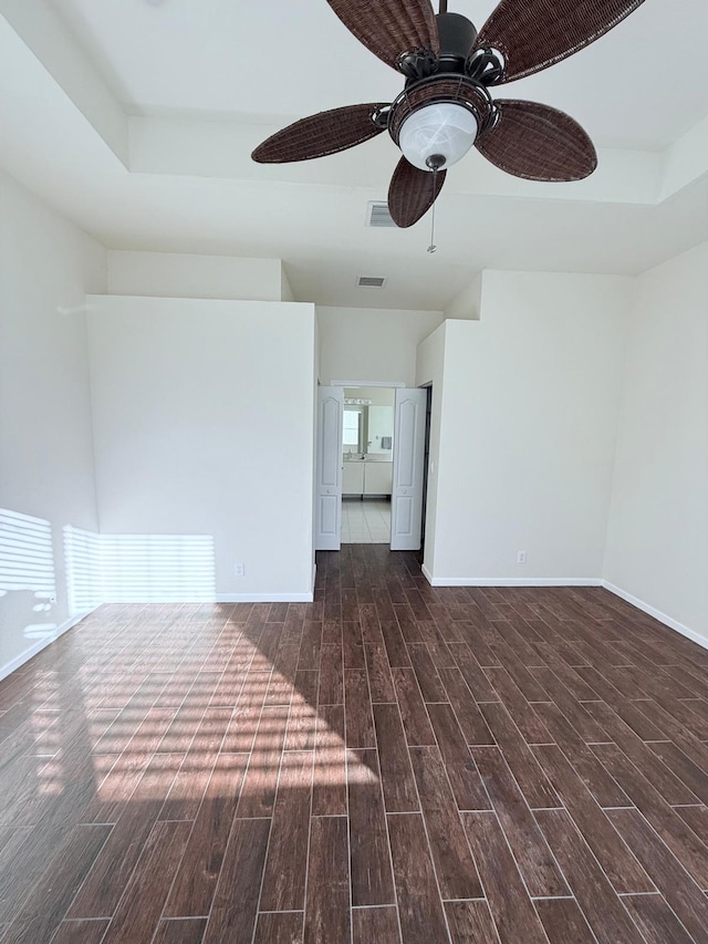 empty room with ceiling fan and a tray ceiling
