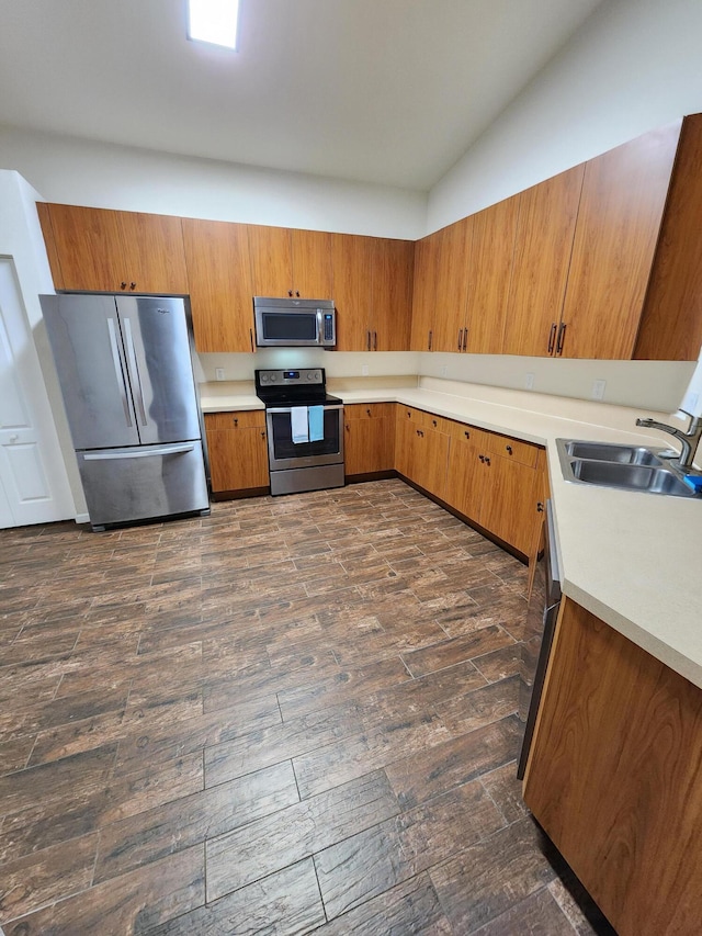 kitchen with sink, dark wood-type flooring, vaulted ceiling, and appliances with stainless steel finishes
