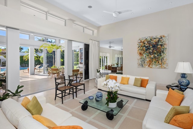 living room with plenty of natural light, a towering ceiling, and ceiling fan