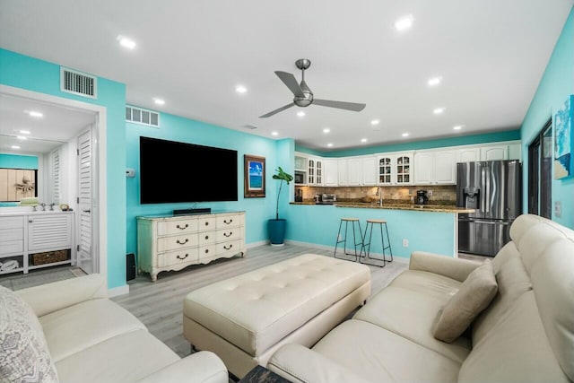 living area with a ceiling fan, light wood-type flooring, visible vents, and recessed lighting