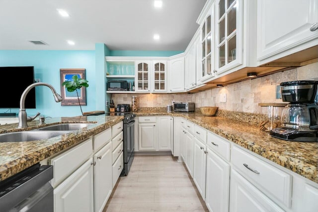 kitchen featuring visible vents, decorative backsplash, white cabinetry, a sink, and black appliances