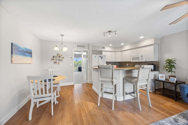 kitchen featuring tasteful backsplash, white cabinets, white appliances, and light hardwood / wood-style floors