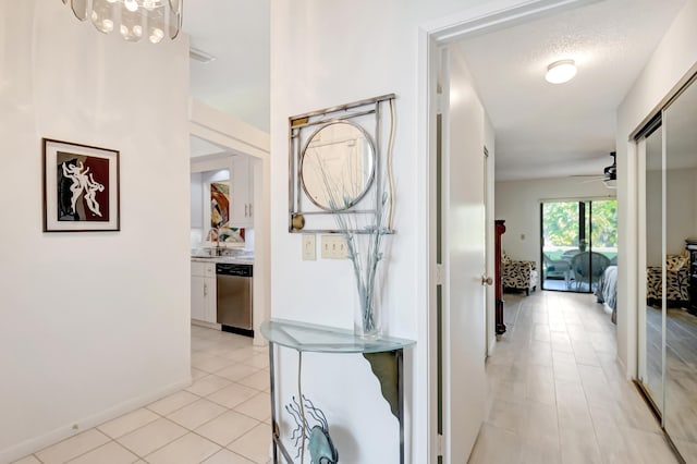 hall featuring light tile patterned flooring, sink, and a textured ceiling