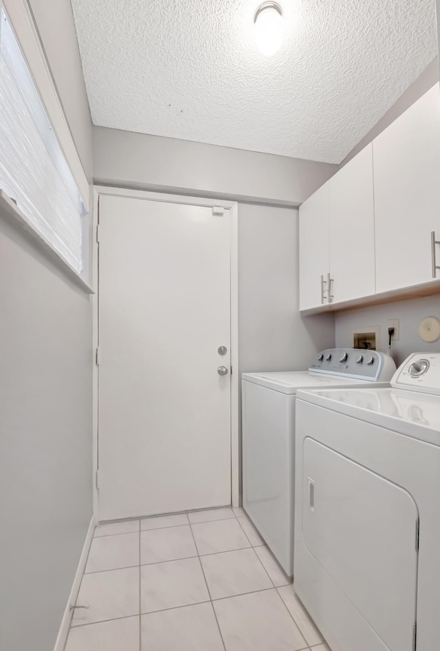 laundry area with cabinets, independent washer and dryer, a textured ceiling, and light tile patterned flooring