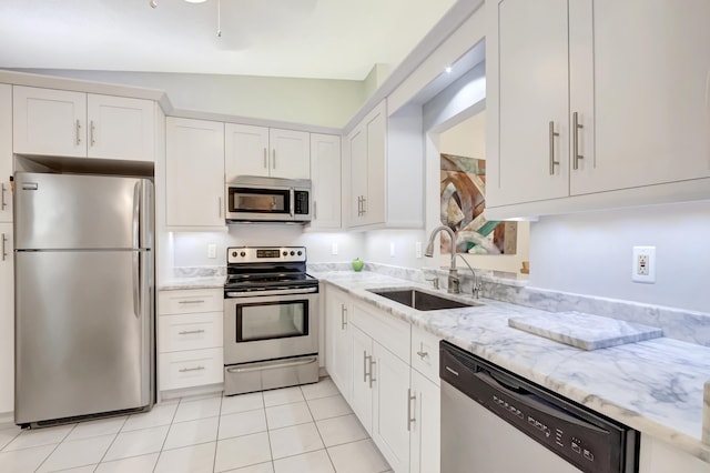 kitchen featuring appliances with stainless steel finishes, white cabinetry, sink, light tile patterned floors, and light stone countertops