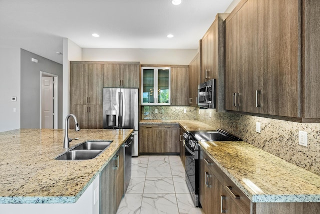 kitchen featuring light stone countertops, appliances with stainless steel finishes, sink, and an island with sink