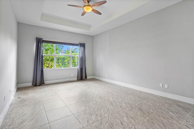 spare room featuring a raised ceiling and ceiling fan