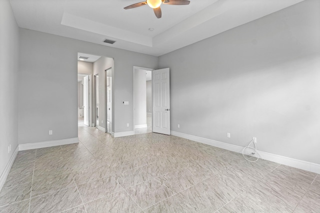 empty room with a raised ceiling and ceiling fan