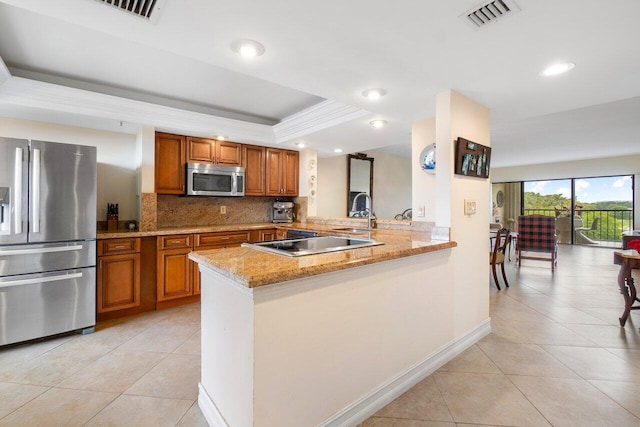 kitchen featuring light tile patterned floors, visible vents, a raised ceiling, appliances with stainless steel finishes, and brown cabinets