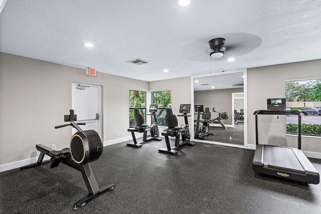 workout area with a healthy amount of sunlight, visible vents, baseboards, and a textured ceiling