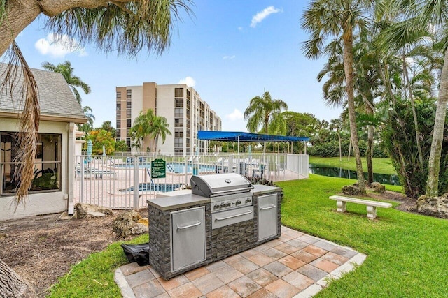 view of patio / terrace with a community pool, fence, and area for grilling