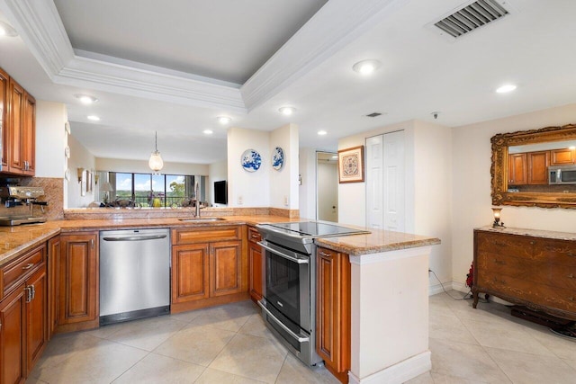 kitchen featuring stainless steel appliances, a sink, visible vents, brown cabinetry, and a raised ceiling